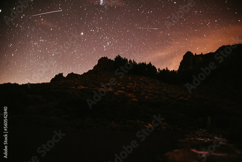 Mountains at night and stars in the sky, the big bear, falling stars and planets in the sky. Noisy photo at long exposure