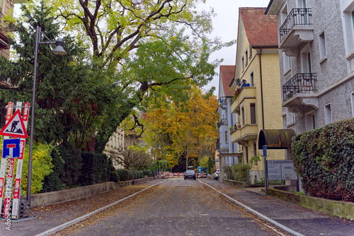 Street with parked car and autumn trees at Swiss City of Baden, Canton Aargau, on a gray cloudy autumn day. Photo taken November 13th, 2022, Baden, Switzerland.