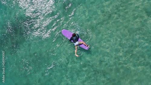 Aerial drone top down photo of surfers having surfing lesson in tropical exotic wavy bay with deep emerald sea