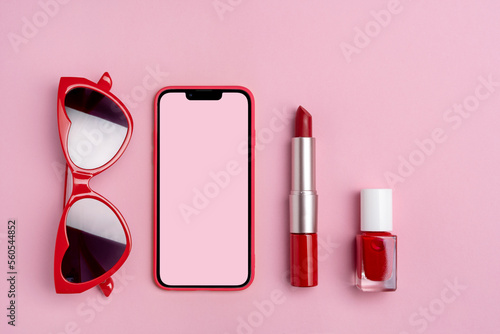 Set of sunglasses, phone, red lipstick and nail polish on pink background. Valentines day background