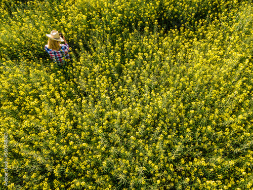 aerial view of a girl taking a picture of a rapeseed field