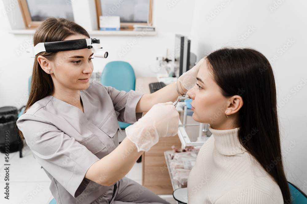 Consultation with ENT doctor. Otolaryngologist examines girl nose before procedure of endoscopy of nose. Rhinoscopy of woman nose. Consultation with ENT doctor. Otolaryngologist examines girl nose before procedure of endoscopy of nose. Rhinoscopy of woman nose.