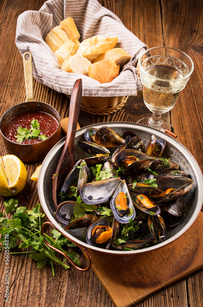 Traditional Italian sailors mussel in red wine wine sauce with vegetables and baguette served as close-up in a classic cataplana casserole