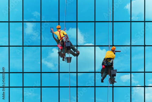 Two workers washing windows of the modern building	