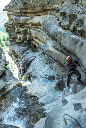 Man on a via ferrata cleaning his glasses