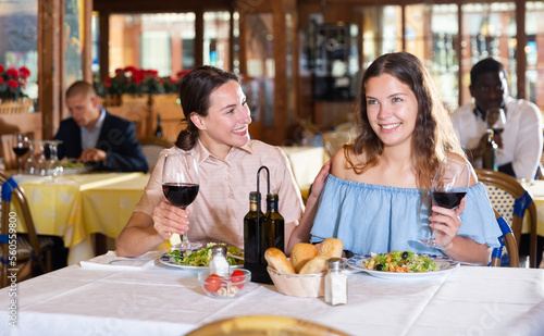 Two young female friends smiling at dinner in a restaurant  celebrating something