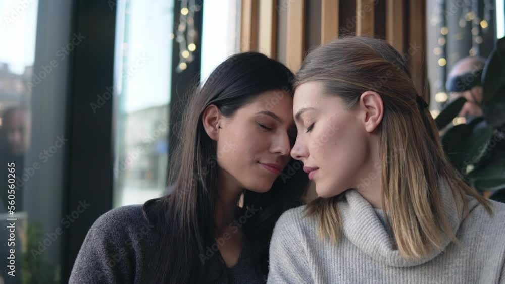Gay female couple have postive expressions, sit close to each other at cafeteria, laughing joyfully. Lesbians couple and love concept Gay female couple have postive expressions, sit close to each other at cafeteria, laughing joyfully. Lesbians couple and love concept