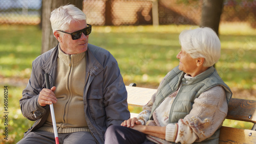 Blind senior man with sunglasses on resting with his wife on a bench in the park. High quality photo © CameraCraft