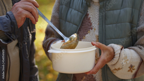 Senior people treating themselves with free charity soup outdoor. No face. High quality photo