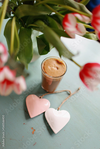 Bouquet of tulips on the table with coffee and hearts. Valentines, mothers, womens day, wedding or birthday flat lay concept. Top view.