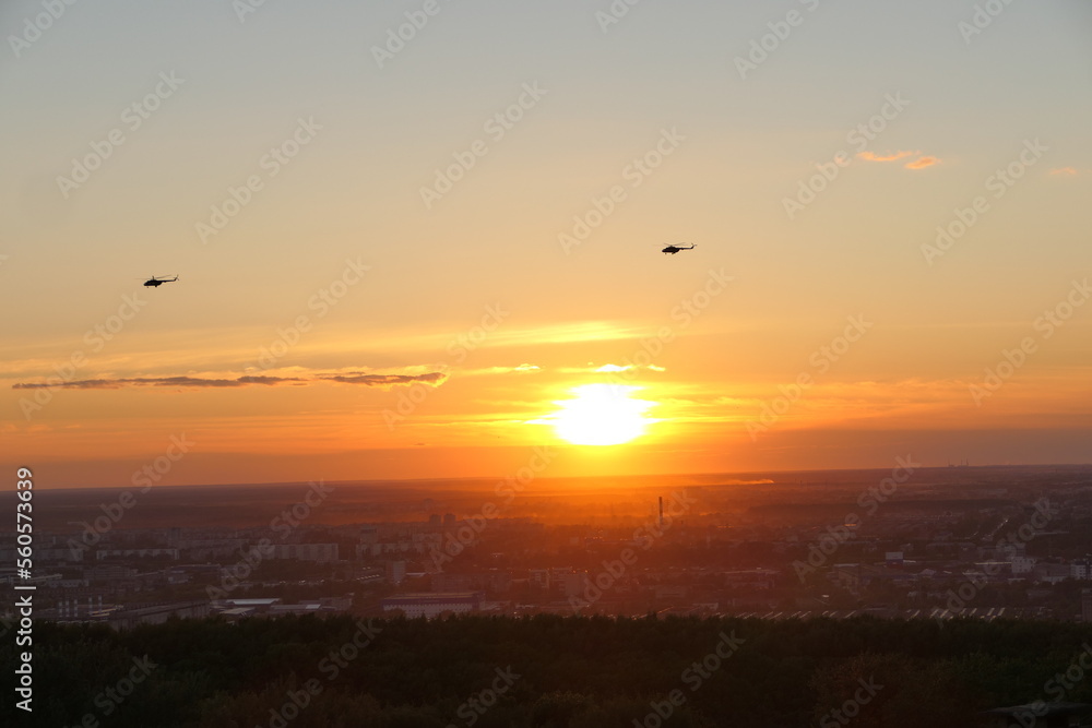 Two helicopters in the sky against the backdrop of the setting sun, Bright sunset.