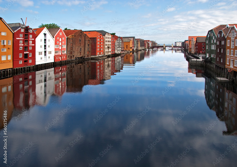 panoramic view of old colorful wooden houses with reflections in river Nidelva in the Brygge district in Trondheim, Norway