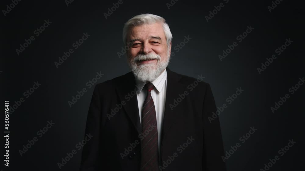 Portrait of a gray-haired, caucasian man smiling and looking at camera. Close-up view of retired businessman wearing black formal suit. High quality 4k footage Portrait of a gray-haired, caucasian man smiling and looking at camera. Close-up view of retired businessman wearing black formal suit. High quality 4k footage