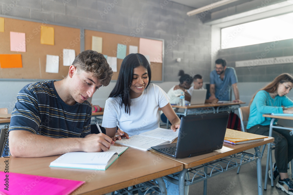 Fototapeta premium Teenager classmates doing exercise and working together in the Secondary School Classroom - Multi ethnic caucasian and Latin American students