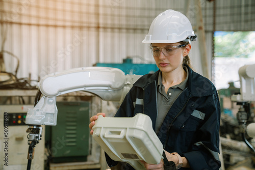 Female engineers or worker is controlling robot arm machine welding steel, worker using forcing welding with a control screen which is used for precision welding control.