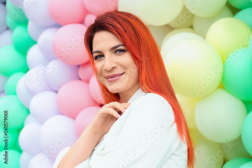 Young woman with bright dyed hair near colorful balloons