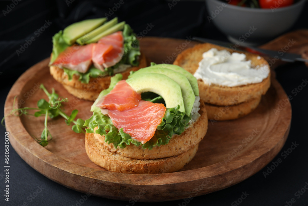 Tasty rusks with salmon, cream cheese and avocado served on black table, closeup Tasty rusks with salmon, cream cheese and avocado served on black table, closeup
