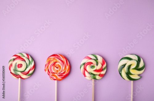 Many colorful lollipops on violet background, flat lay. Space for text