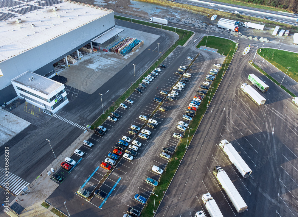 Aerial view of a factory and factory parking lot with cars and trucks parked