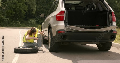 Female driver trying to change tire by herself