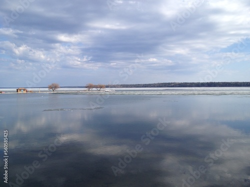 calm lake with overcast clouds reflecting off the lake with trees on the horizon