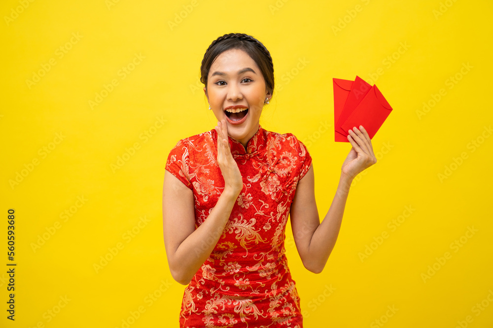 Beautiful Asian woman wearing traditional cheongsam with red envelope isolated on yellow background, Happy Chinese New Year. Beautiful Asian woman wearing traditional cheongsam with red envelope isolated on yellow background, Happy Chinese New Year.