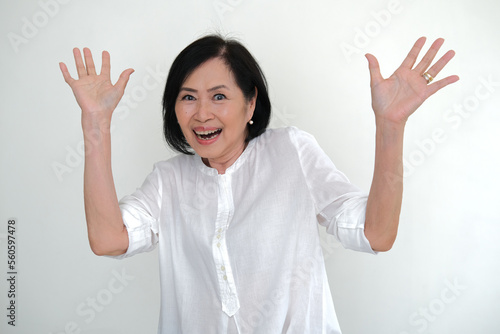 A woman in white looking happy with both hands in the air photo