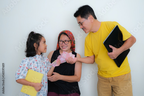 A daughter thanking her father for giving her some money for school allowance photo