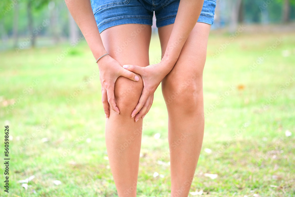 Knee pain. Woman standing at the park. hands on knees .She massaged her knees to ease the pain. Knee pain. Woman standing at the park. hands on knees .She massaged her knees to ease the pain.