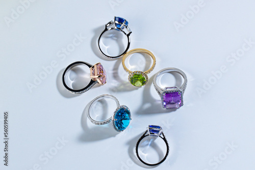 Six rings with bright gemstones tourmaline, topaz, amethyst, chrysolite, sapphire, aquamarine on white background with shadows. High quality photo