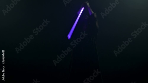 Young man in Jedi cosplay costume with lightsaber battle on black background in smoke and rain, 4k slow motion video filmed on 8k camera nikon z9 photo