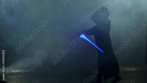 Young man in Jedi cosplay costume with lightsaber battle on black background in smoke and rain, 4k slow motion video filmed on 8k camera nikon z9 photo