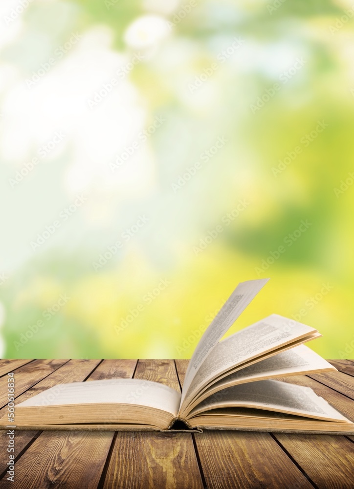 Open book on desk on desk with bright autumn background Open book on desk on desk with bright autumn background
