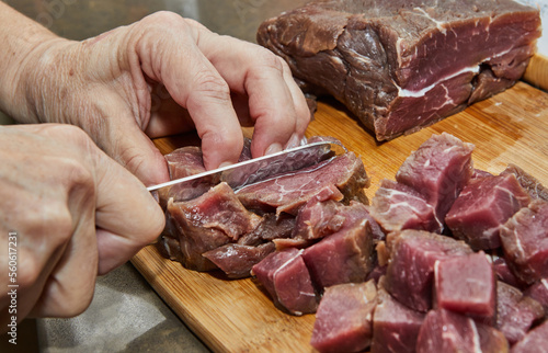 Chef cuts the beef meat into cubes for cooking