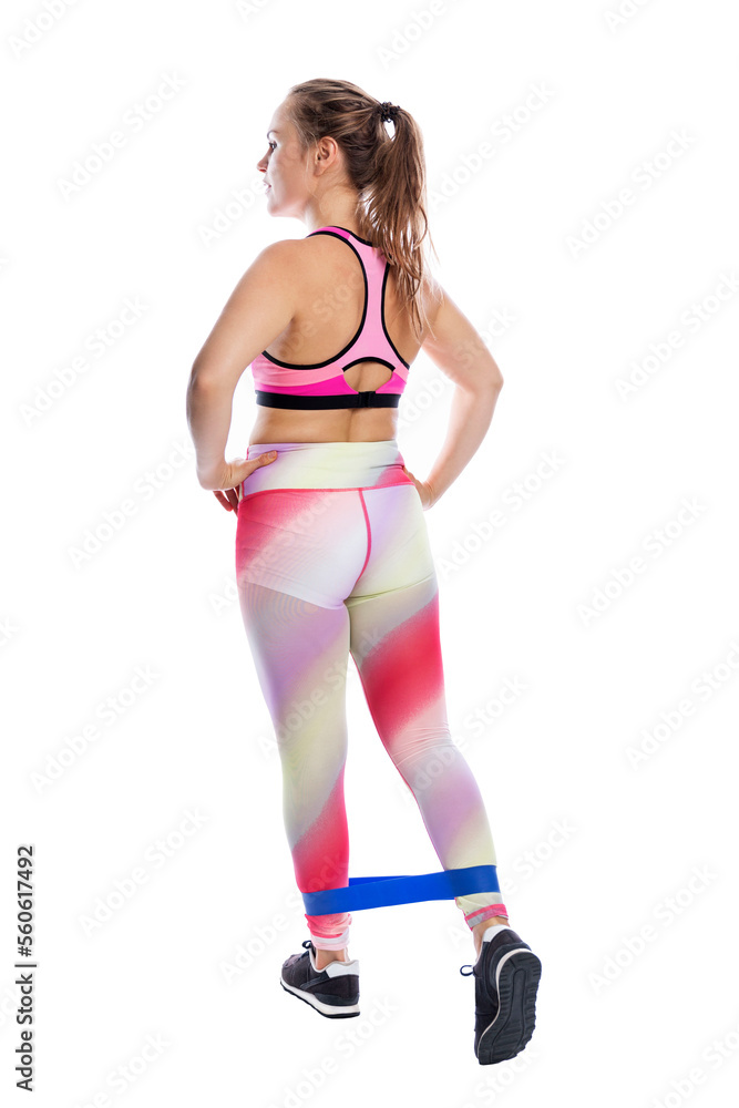 young woman is engaged in fitness with an elastic band on her legs. Beautiful brown-haired woman in bright sportswear. Health, sports and activity. Full height. Isolated on white background. young woman is engaged in fitness with an elastic band on her legs. Beautiful brown-haired woman in bright sportswear. Health, sports and activity. Full height. Isolated on white background.