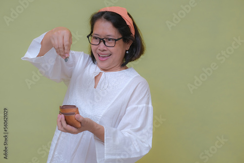 Asian woman standing and dropping some rupiah coins into small leather wallet photo