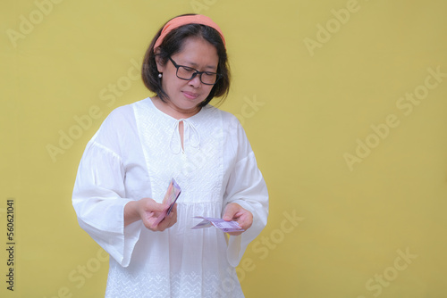 Woman wearing white and hair band, counting some rupiah cash money photo