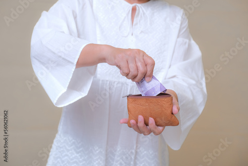 Woman putting some small Rupiah change into little leather wallet to save photo