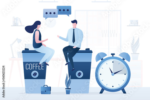 Office workers sit on large mugs of coffee and talk. Alarm clock, coffee break, colleagues talking work. Pause in work process, rest, recharge. Office workflow, room interior on background.