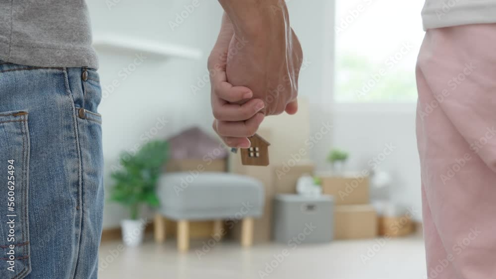 Moving house, relocation. Couple hold key house keychain in new apartment, inside the room was a cardboard box containing personal belongings and furniture. move in the new apartment or condominium Moving house, relocation. Couple hold key house keychain in new apartment, inside the room was a cardboard box containing personal belongings and furniture. move in the new apartment or condominium