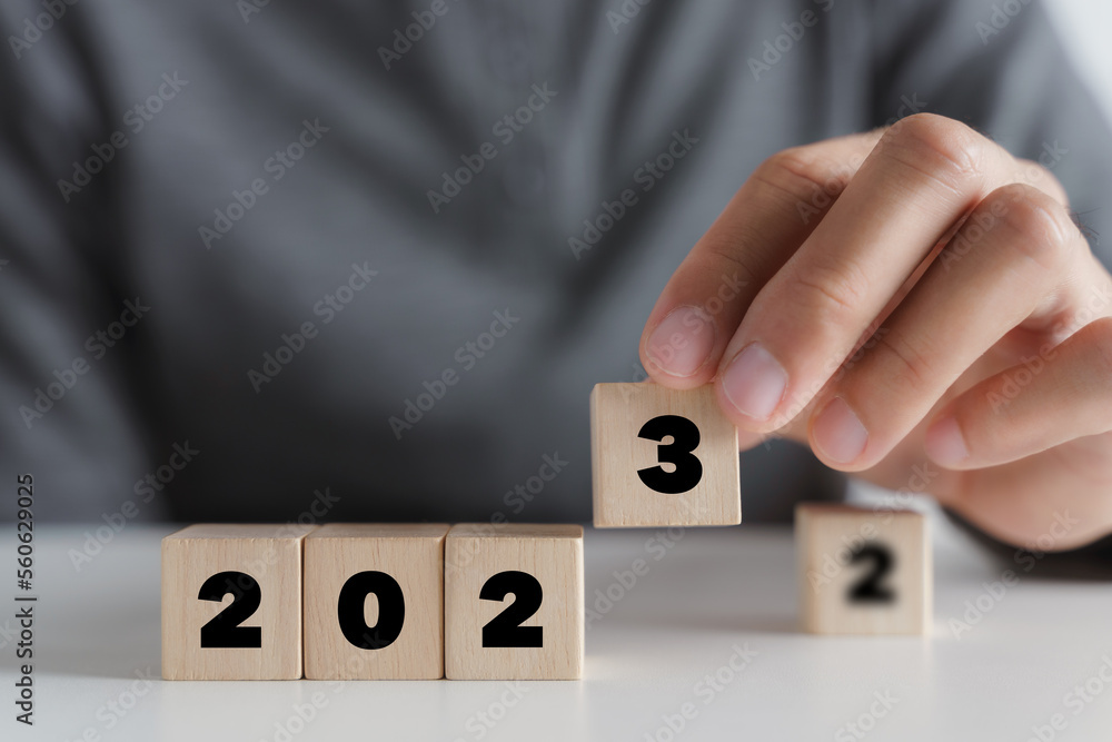 Man hand putting wooden cube block to change 2022 year to 2023 year. start to year 2023. happy new years concept. Man hand putting wooden cube block to change 2022 year to 2023 year. start to year 2023. happy new years concept.