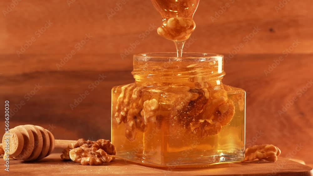 Honey flowing from a wooden spoon full with nuts in a honey jar. Wood texture background. Concept 4k video for healthy breakfast. Honey flowing from a wooden spoon full with nuts in a honey jar. Wood texture background. Concept 4k video for healthy breakfast.