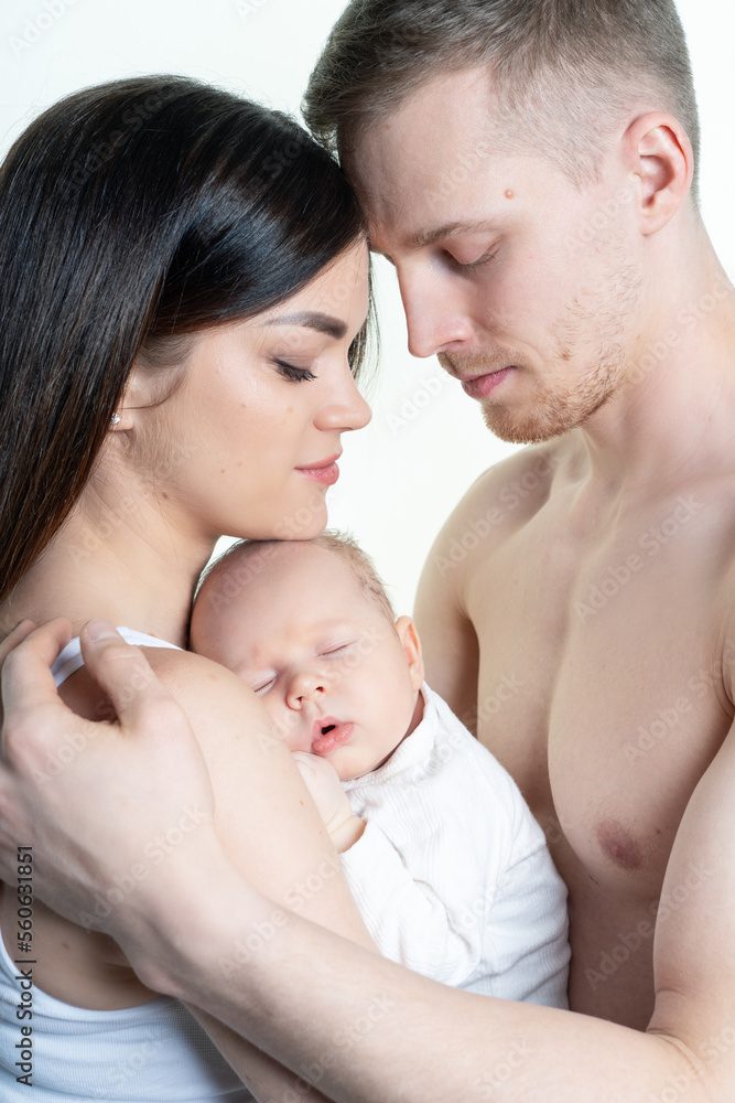 Parents hold a newborn baby in their arms. On a white background, in the studio. close-up Parents hold a newborn baby in their arms. On a white background, in the studio. close-up