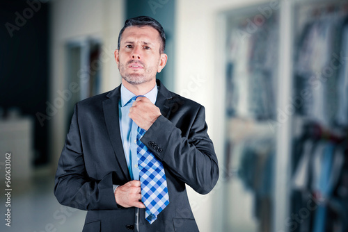 Handsome caucasian businessman in grey suit tying the necktie