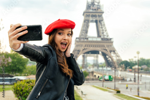 Beautiful young woman visiting paris and the eiffel tower. Parisian girl with red hat and fashionable clothes having fun in the city center and landmarks area