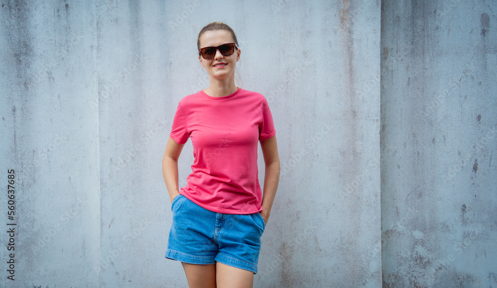 Female model wearing pink blank t-shirt on the background of an gray wall. Female model wearing pink blank t-shirt on the background of an gray wall.