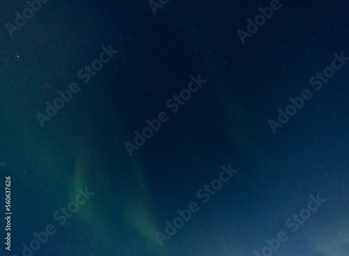 Green and purple northern lights in iceland with the sky bluish by the moon