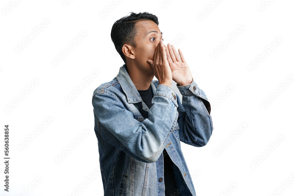 asian man wearing blue jean jacket shouting giving information with hand near mouth, isolated on white background asian man wearing blue jean jacket shouting giving information with hand near mouth, isolated on white background
