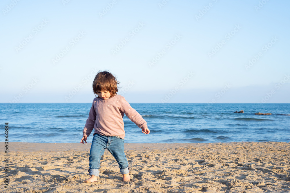 Cheerful female toddler running at the beach.