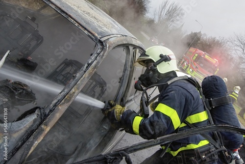 Firefighter with a breathing apparatus mask extinguishes a car fire using water